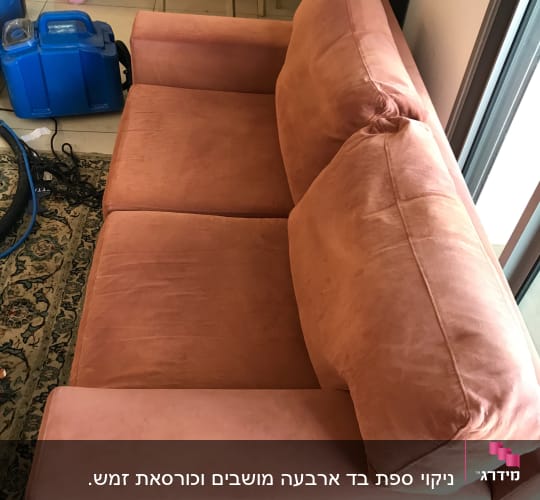 ספה כתומה עם מכונת ניקוי כחולה ליד